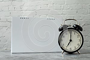 Classic clock with blank calendar note on brickwall background