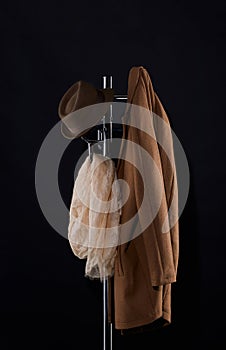 classic coat, hat and scarf hanging on coat rack on black