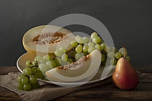 Classic composition with melon, grape and pear. Still life.