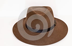Classic cowboy brown felt hat with strap and copper closure on white background