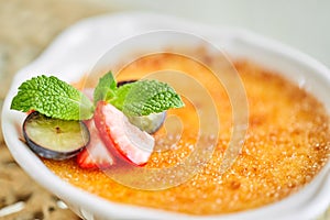 Classic creme brulee in glass bowl. Appetizing ice cream close up. Delicious dessert with grape and strawberry Sugary