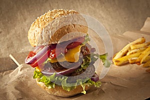 Classic deluxe cheeseburger with lettuce, onions, tomato and pickles on a sesame seed bun