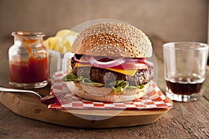 Classic deluxe cheeseburger with lettuce, onions, tomato and pickles on a sesame seed bun