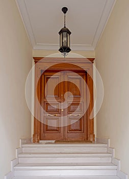 A classic design house entrance with private portico and marble stairs to a natural wood door.