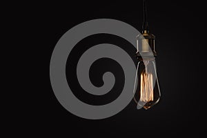 Classic Edison light bulb on black background photo