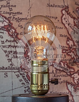 Classic edison light bulb with looping carbon filament on map ba