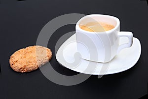 Classic espresso in white cup with homemade cake on black background. Selective focus.