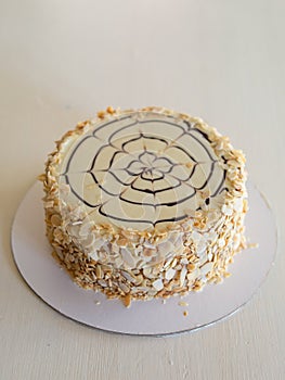 Classic Esterhazy cake decorated with almond petals and a chocolate spider on a white background.