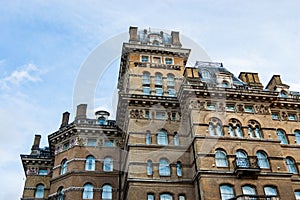 Classic facade of the building decorated with arcs, sculptures, metal railings and other elements. London brick architecture