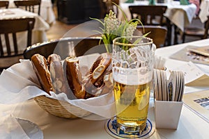Classic German dinner of fried sausages with braised cabbage on large white plates with light beer, standing on table in
