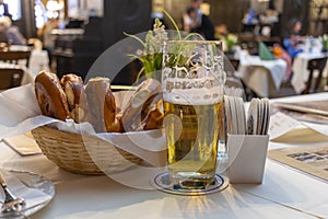Classic German dinner of fried sausages with braised cabbage on large white plates with light beer, standing on table in