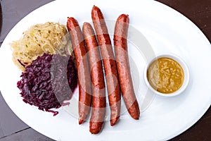Classic German snacks, sausages with mustard cabbage and bagel on a white plate