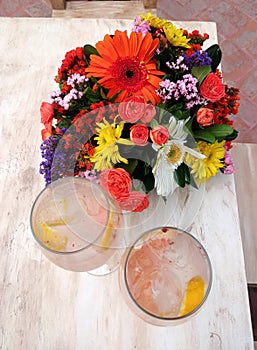 Classic Gin drink cocktail shaked with grapefruit in elegant glasses next to colorful flowers on an elegant table photo