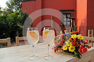 Classic Gin drink cocktail shaked with grapefruit in elegant glasses next to colorful flowers on an elegant table photo