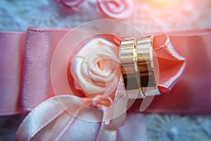 Classic gold wedding rings on pink ribbons, close-up, selective focus. Vintage photography of the wedding day