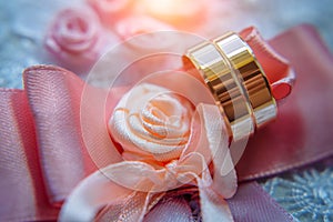 Classic gold wedding rings on pink ribbons, close-up, selective focus. Vintage photography of the wedding day