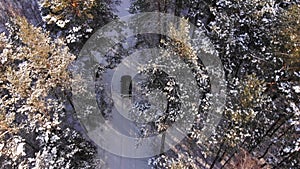 Classic gray car driving through the white winter snowy forest on country road. Top view. Winter or alpine road in the