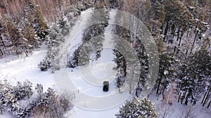 Classic gray car driving through the white winter snowy forest on country road. Top view. Winter or alpine road in the