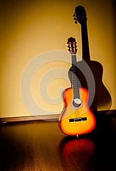 Classic guitar standing near wall under beam of light