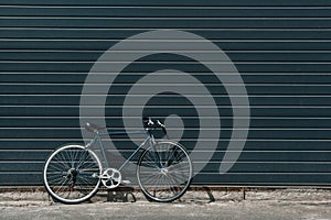 Classic hipster bicycle standing near black wall outdoors