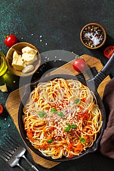 Classic homemade italian spaghetti pasta with tomato sauce, cheese parmesan and basil on dark stone table. Top view, flat lay