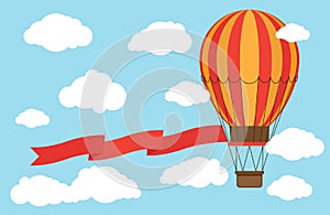 Classic hot air balloon with red ribbon flying from sky and clouds