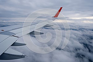 Classic image through aircraft window onto wing. Flight view over clouds