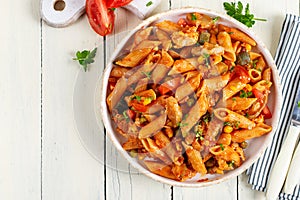 Classic italian pasta penne arrabbiata with vegetables on white wooden table.