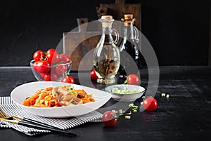 Classic italian pasta penne marinara with mussels and green onions on dark table.