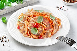 Classic Italian pasta with tomato sauce and basil on a light background close-up.