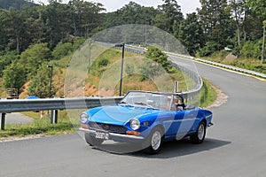 Classic blue italian sports car on downhill road