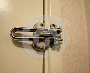 Classic large, sturdy metal latch securing a hotel or motel door to keep out intruders and unwanted guests