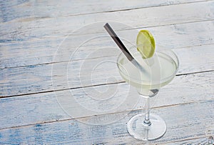 Classic lime margarita cocktail with sliced limes on wooden background.