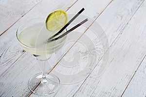 Classic lime margarita cocktail with sliced limes on wooden background.