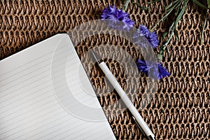 Classic lined notebook and pen in a natural rustic table setting with soft selected focus