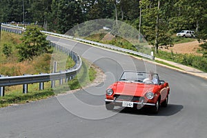 Classic little red italian sports car on downhill road