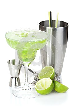 Classic margarita cocktail with salty rim, limes and drink utensils