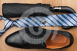 Classic mens shoes, tie, umbrella,cufflinks on the wooden floor