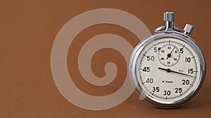 Classic metallic chrome mechanical analog stopwatch isolated on brown background