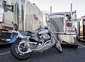 Classic motorcycle as an alternative mode of transport and a hobby of a truck driver while resting is parked near a row of big rig