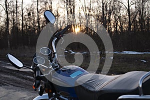 Classic motorcycle with sunset background, black leather seat, dashboard with speedometer and rear view mirrors on the