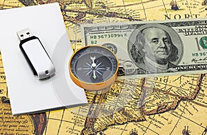 Classic navigation compass on American dollars flash drive on white paper on old vintage world map as symbol of tourism with compa