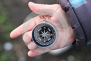 Classic navigation compass in childs hand on natural background