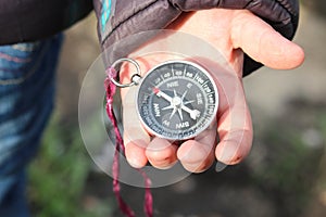 Classic navigation compass in childs hand on natural background