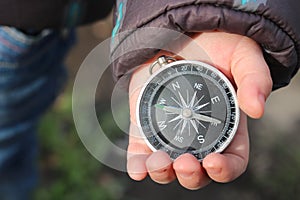 Classic navigation compass in childs hand on natural background