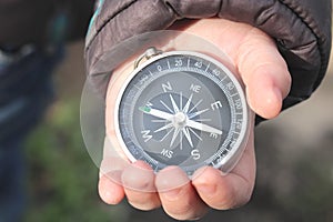 Classic navigation compass in childs hand on natural background