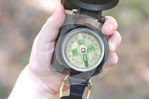 Classic navigation compass in childs hand on natural background