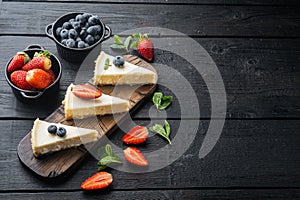 Classic New York Cheesecake sliced, on black wooden table background with copy space for text