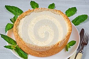 Classic New York cheesecake on the white plate decorated with fresh mint leaves on the gray kitchen background