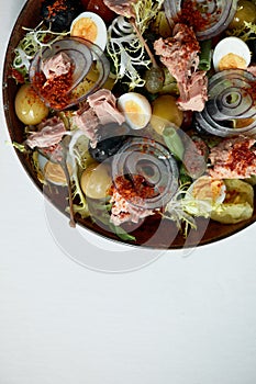 Classic nicoise in the author's serving tuna salad with fresh vegetables on a white napkin, canned tuna with masilnas